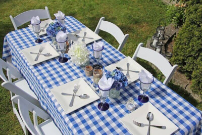 Adorable Outdoor Father’s Day Décor Featuring Tablecloth, Faux Floral, Plates, Cutlery, & Chairs