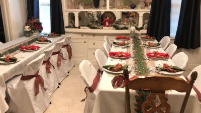 Classy Christmas Dinner Party Setup With Tablecloths, Garlands, Plates, Napkins, & Chair Sashes