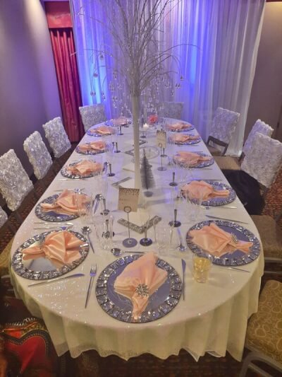 Whimsical Table Setup With Tablecloth, Chargers, Napkins, Cutlery, Glasses, Candles, & Chair Covers