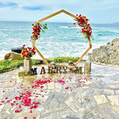 Beach Proposal Backdrop Using Backdrop Arch, Flowers, Marquee Lights, Petals, & Risers