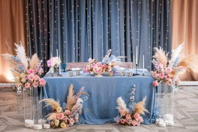 Vibrant Wedding Table Setup with Drapes, Tablecloth, Feathers, Flowers, Candles, Vases and String Li