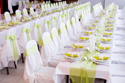 Green and White Long Table with Table Linens, Chair Covers, Disposable Dinnerware, and Centerpieces