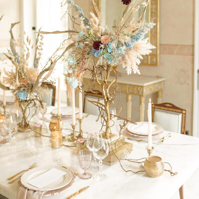 Fanciful Table Arrangement With Charger, Napkin, Cutlery, Candle, Candle Holder, Floral, & Dry Grass
