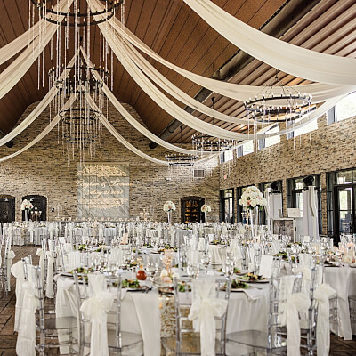 Elegant Indoor Wedding Setup Using Drapes, Tablecloths, Chair Sashes, Flowers & Candelabras