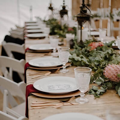 Elegant Rustic Tablescape With Chargers, Napkins, Cutlery, Chairs, Leaf Garland, Lanterns, & Candles