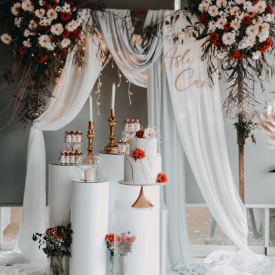 Mesmerizing Wedding Cake Table Setup Using Backdrop Stand, Drapes, Flowers, & Dessert Stands 