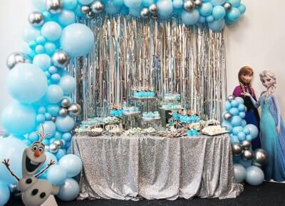 Enchanting Frozen Themed Party Setup with Tablecloth, Fringe Curtains, Cupcake Stand & Balloons