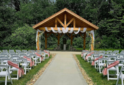Rustic Garden Wedding Ceremony with Draped Aisle Chairs and White Draped Pavilion Beam