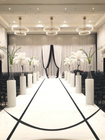 Chic Monochrome Walkway with Tall Glass Vases, White Pedestals, and an Elegant Draped Backdrop
