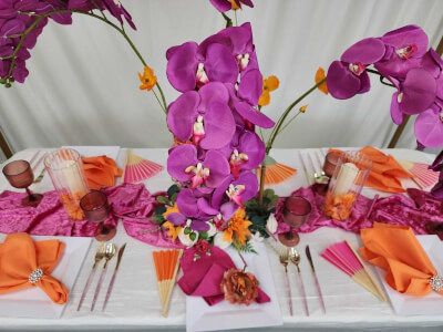 Vibrant Orchid Blooms with Fuchsia and Orange Table Setting, Glass Candle Holders and Fan Accents