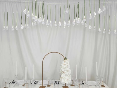 Minimalist White Tablescape with Floating Flowers, Draped Backdrop, and Tall Candle Accents
