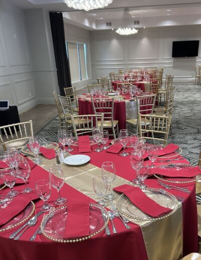 Elegant Banquet Style with Red Table Covers, Gold Runners, Beaded Chargers, and Crystal Glassware