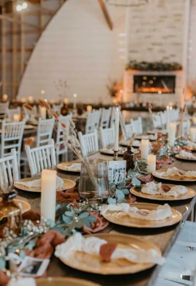 Rustic Farmhouse Style Reception with Gold Chargers, Cheesecloth Napkins, Greenery, and Candles