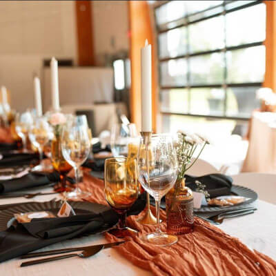 Stylish Contrast Featuring Black Dinnerware and Terracotta Runner, with Amber Goblets and Candlelit