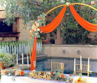 Romantic Poolside Wedding Setup with Orange Drapes, Round Backdrop Stand & Floral Details