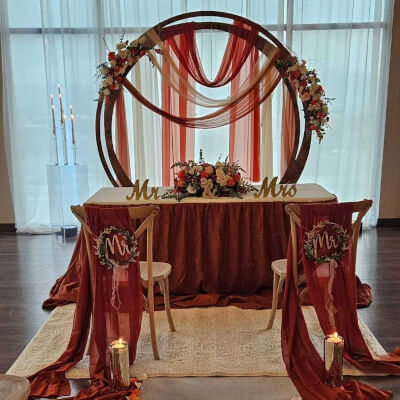 Warm Terracotta Sweetheart Table with Flowing Drapes, Round Backdrop & Floral Accents