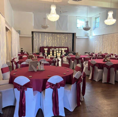 Embracing Elegance in Burgundy Linens, Chair Sashes, Warm Lighting & LOVE Sign