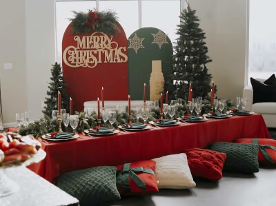 Festive Christmas Setup with Floor Seating, Red & Green Accents, and Merry Backdrop