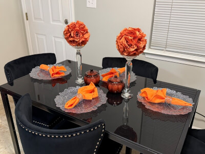 Chic Black Table Setting with Clear Reef Chargers, Orange Napkins, and Kissing Ball Centerpieces