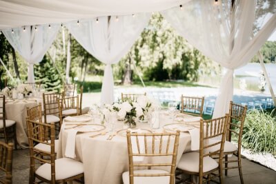Elegant Garden Event Setting with Neutral Table Covers, Draped Canopy, & Fresh White Florals
